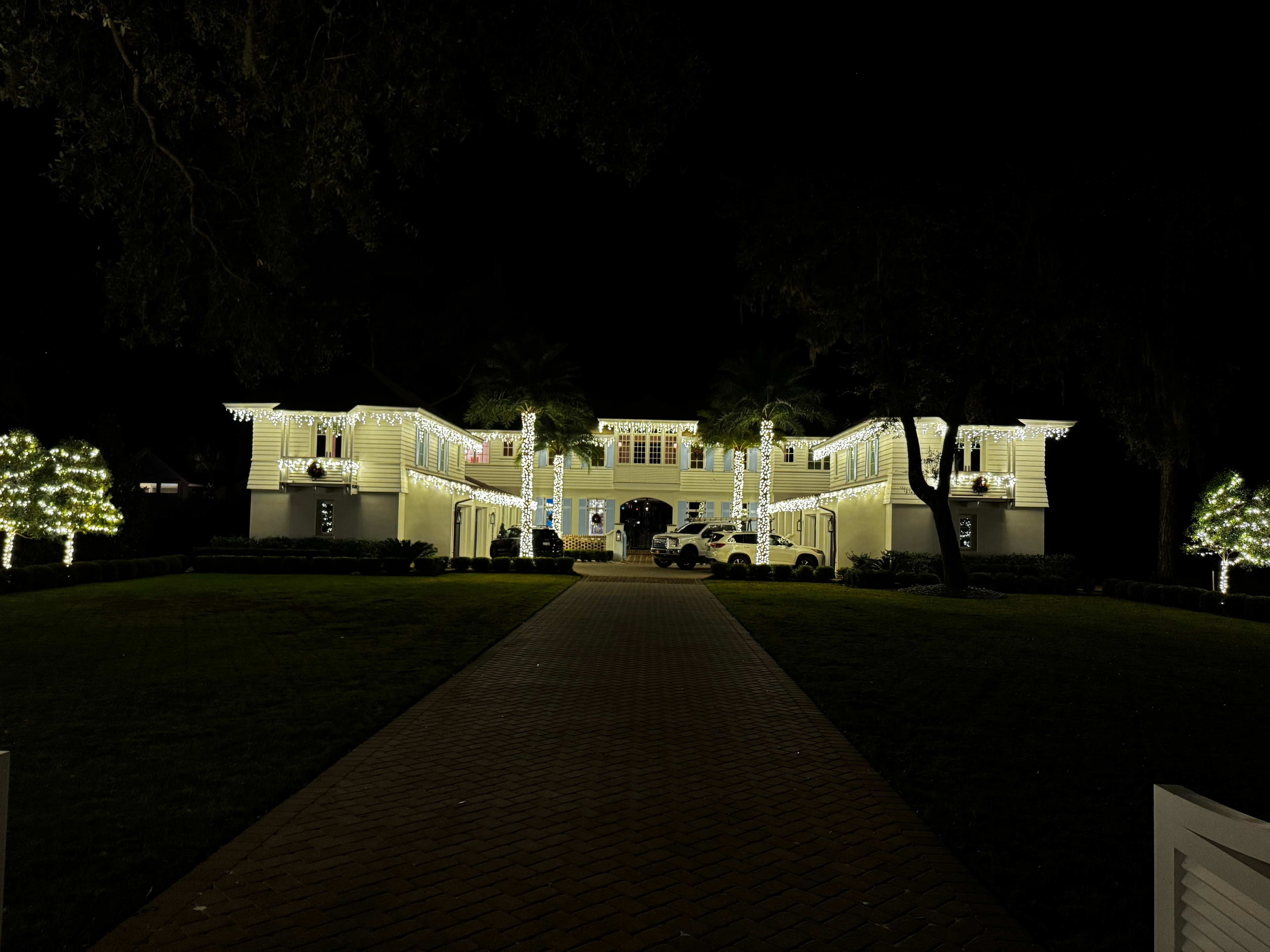 48 Wide Water estate fully lit with icicle lights, wrapped palms, and illuminated trees
