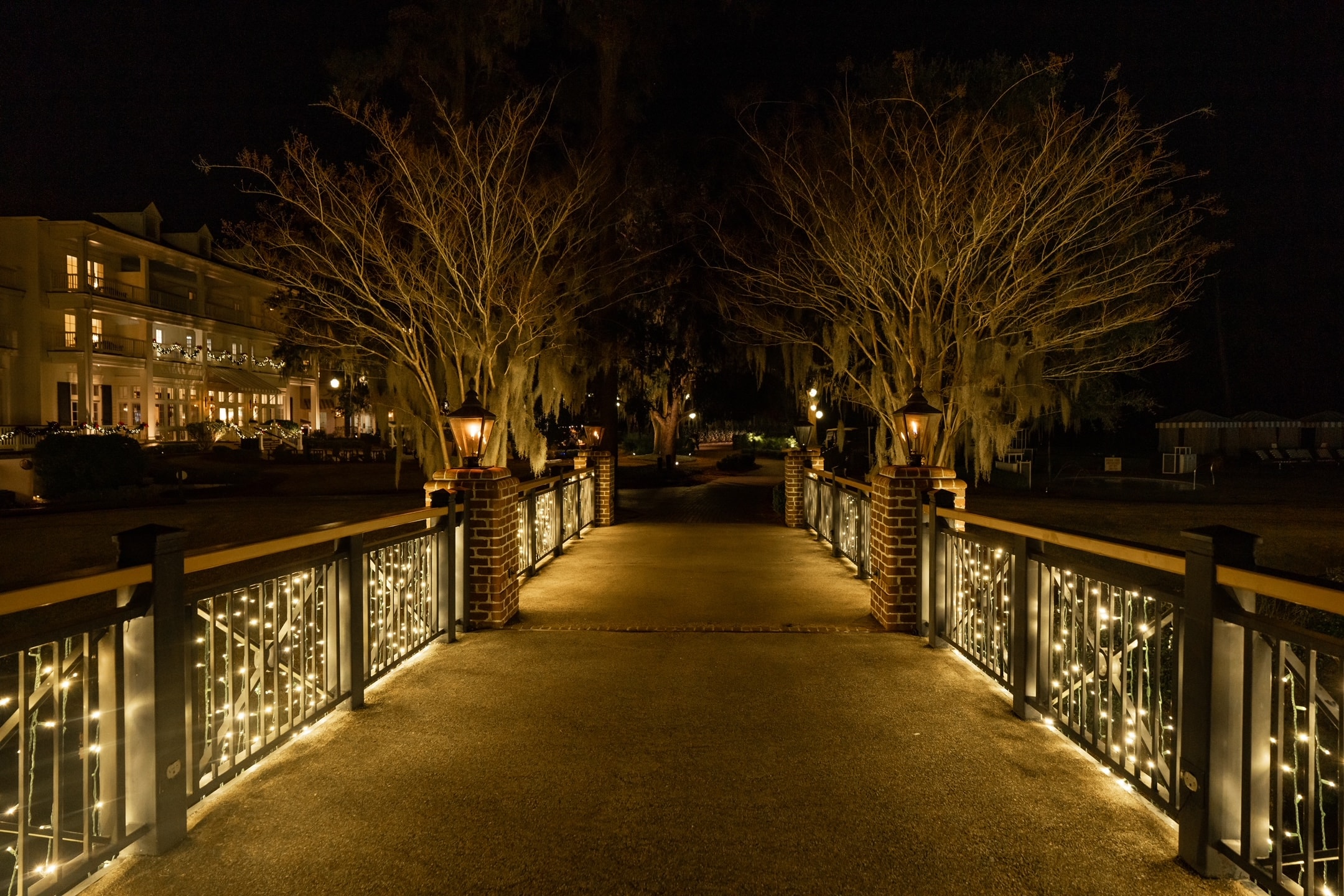 Elegant holiday-lit walkway bridge with gas lanterns and warm white rail lights