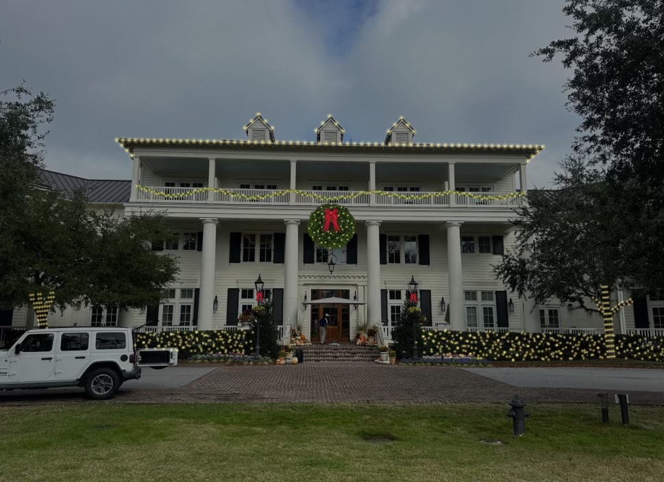 Grand plantation-style manor with full roofline lights, balcony garland, and large wreath