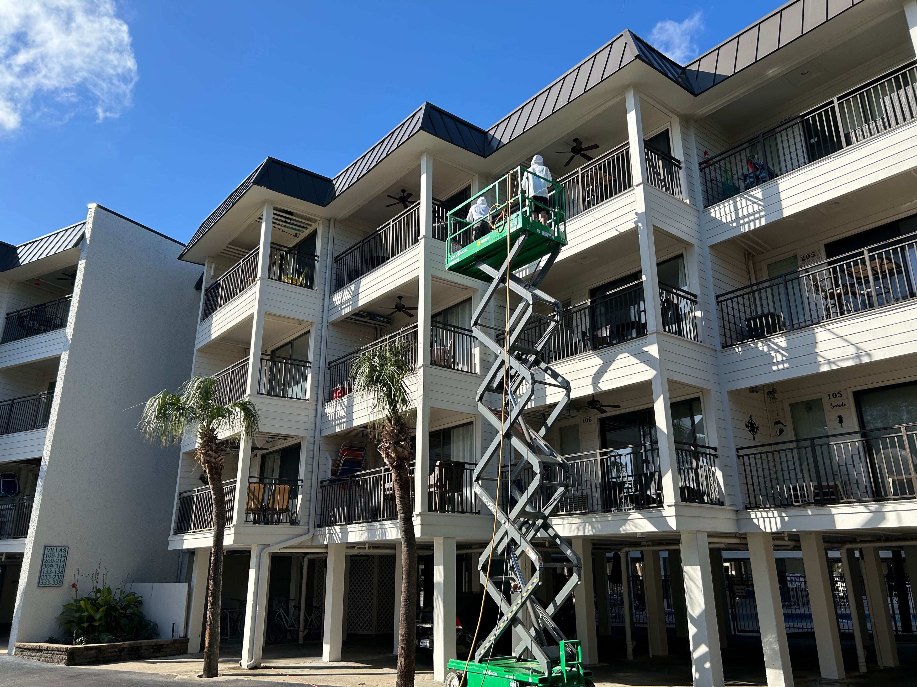 Prime Time crew on scissor lift washing a multi-story coastal building