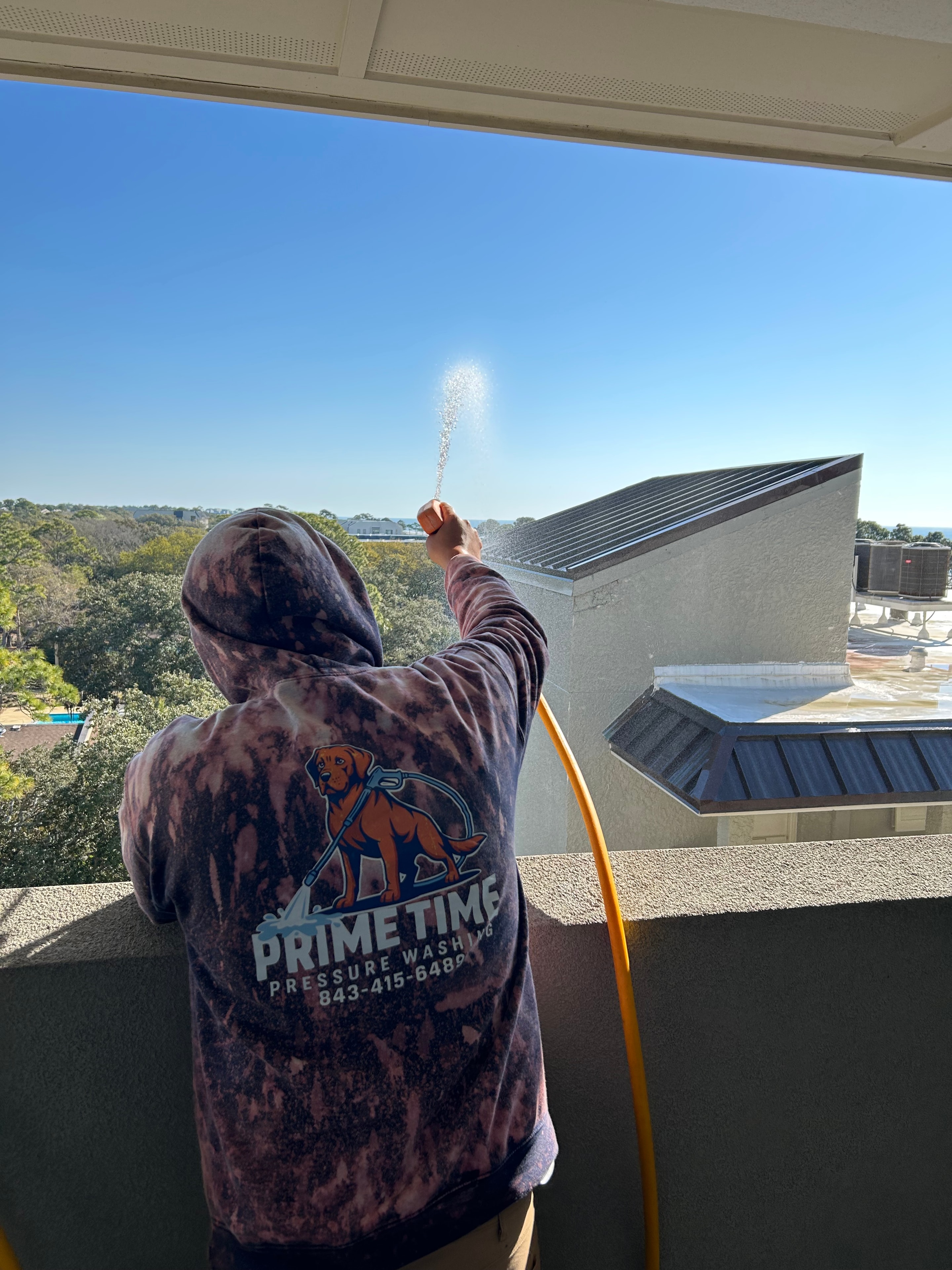 Prime Time technician soft washing a commercial building exterior